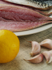 Close up of raw fillet of mackerel, lemon and garlic cloves.