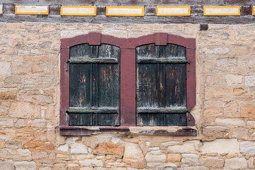 Fototapeta na wymiar Windows with closed shutters in a sandstone wall