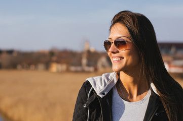 Close up portrait of a happy smiling young woman outside with sunglasses