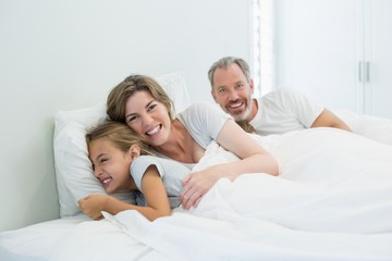Fototapeta premium Happy family lying together on bed in bedroom at home
