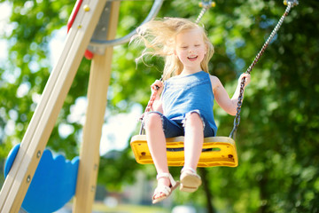 Cute little girl having fun on a playground outdoors in summer