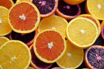 Fototapeta na wymiar Tray of oranges, blood oranges, and cara cara oranges cut in half 