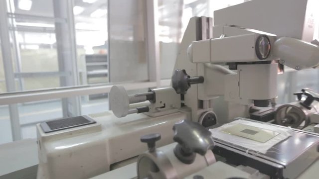 Researchers working. Equipment for testing printed circuit boards on different defects. Microscope in a laboratory. Medicine manufacturing and lab equipment. Camera turns left