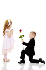 The boy gives the girl a flower.