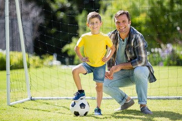 Father and son with football in the park on a sunny day