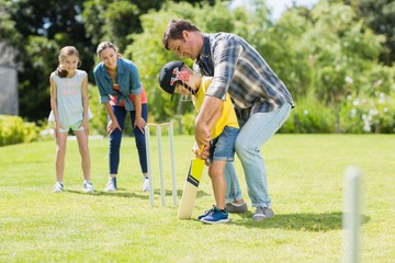 Happy family playing cricket together