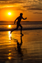 Fototapeta na wymiar Silhouette of young male capoeira dancer, yoga and martial art specialist at beach in Mexico during spectacular sunset
