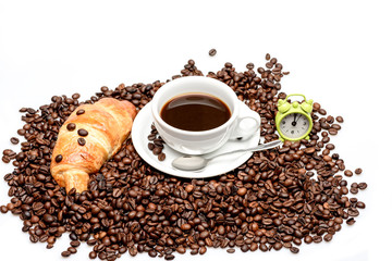 Coffee beans with fresh croissant and cup of coffee