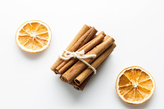 Cinnamon sticks with star orange slices on white background.