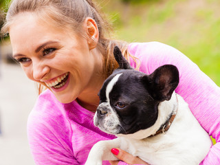 Smiling woman holding french bulldog outside