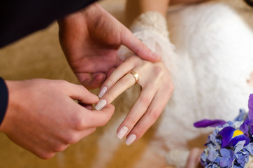Love and marriage. Wedding ceremony up of groom putting golden ring on the bride's finger.