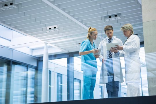 Medical Team Discussing Over Digital Tablet In Corridor