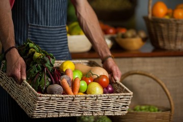 Mid section of male staff holding fresh vegetables 