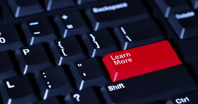 Video footage of male hand pushing a red button with text of Learn More on the computer keyboard