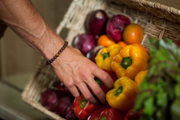 Hand of male staff selecting bell pepper in organic section
