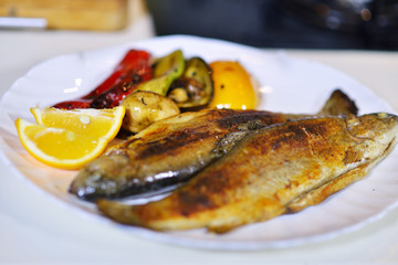 Tasty baked fish on plate on table close-up