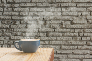 Coffee cup with stream of vapour against white brick wall background.