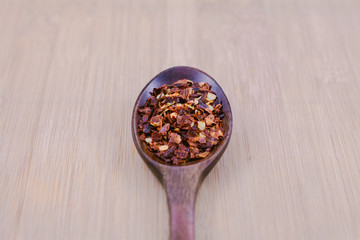 chilli flakes in the wooden spoon over the chop board