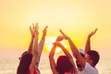 people dancing at the beach with hands up. concept about party, music and people