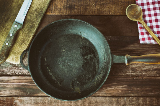 Black cast-iron frying pan with a kitchen board on the table