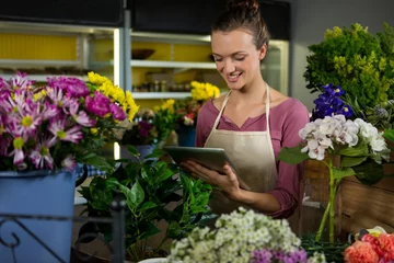 Crédence de cuisine en verre imprimé Fleuriste Female florist using digital tablet in florist shop