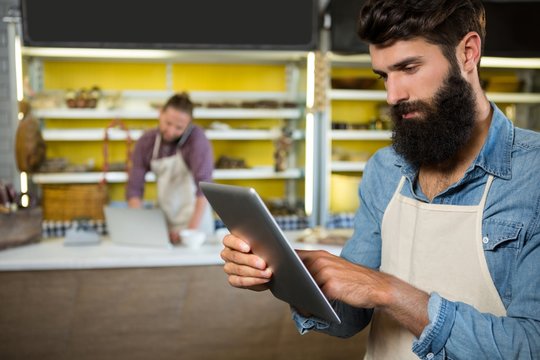Attentive staff using digital tablet at bakery counter
