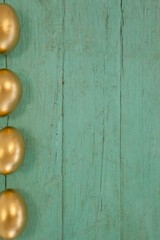 Golden Easter eggs arranged on wooden surface