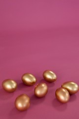 Golden Easter eggs on pink background