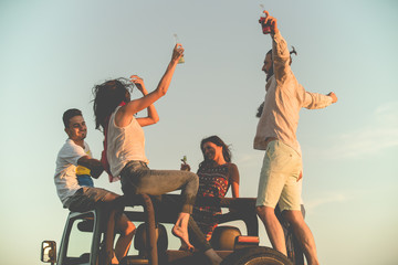 young group having fun on the beach and dancing in a convertible car