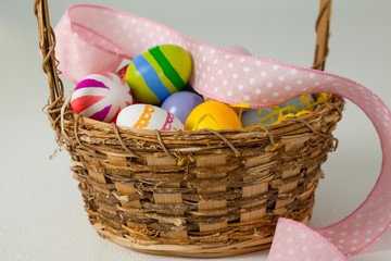 Various Easter eggs with ribbon in wicker basket