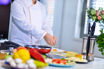 cook chef in kitchen and fresh vegetables on table