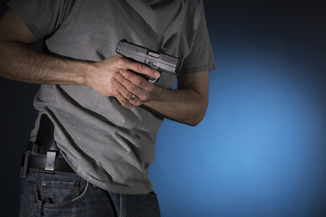 Man drawing a concealed carry pistol from a holster - obrazy, fototapety, plakaty