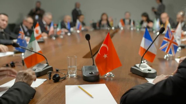 Succesful speech at political negotiations at round table international conference or summit. Workplace of official delegate POV or FPV. Flag of Turkey, microphone, sheet of paper and pencil