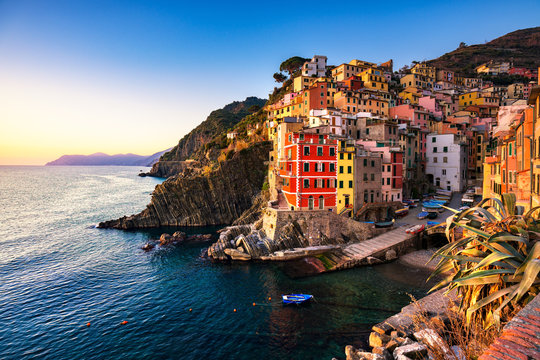 Riomaggiore town, cape and sea landscape at sunset. Cinque Terre, Liguria, Italy