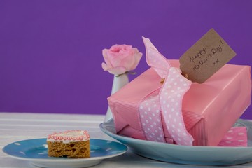 Gift box, flower vase and cookie on wooden surface
