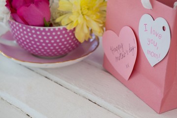 Close-up of paper bag with message and fresh flowers