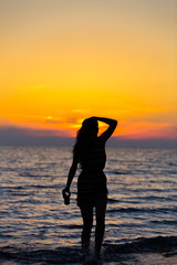 Fototapeta premium Silhouette of a sensual woman at sunrise on the beach, sexy body, perfect figure, enjoying life
