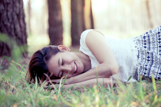 Happy young asian woman lying down on grass in the park in vintage color tone
