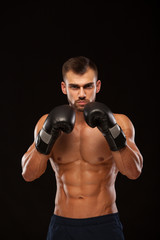 Fototapeta na wymiar Muscular young man with perfect Torso with six pack abs, in boxing gloves is showing the different movements and strikes isolated on black background with copyspace