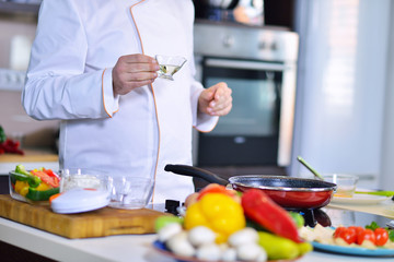 cook chef in kitchen and fresh vegetables on table