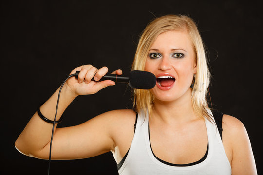 Blonde woman singing to microphone