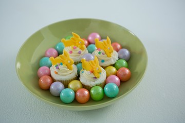 Colorful chocolate Easter eggs with cup cakes in bowl