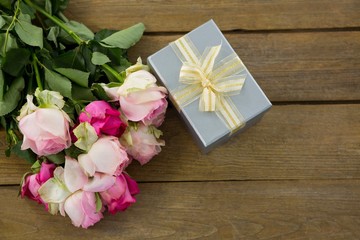 Gift box with bunch of rose on wooden plank
