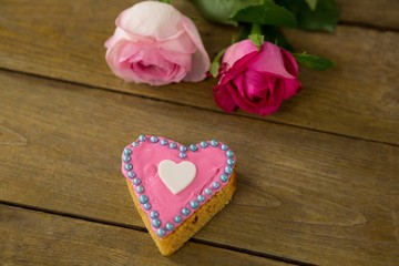 Pink roses with heart shape cookies on wooden plank