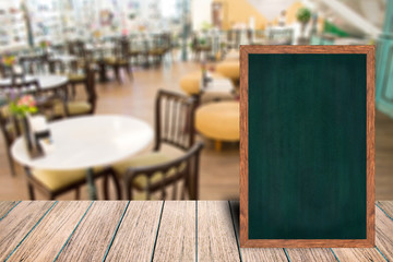 Chalkboard wood frame blackboard sign menu on wooden table, Blurred image background, Template mock up for adding your design and leave space beside frame for adding more text.