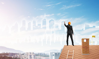 Man architect draw silhouette of modern city on blue sky. Mixed media