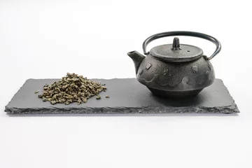 Foto op Aluminium Cast-iron black teapot and handful of leaf green tea on rectangular shale plate © ktv144
