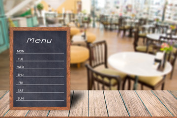 Wooden menu display sign, Frame restaurant message board on wooden table, Blurred image background, Template mock up for adding your design and leave space beside frame for adding more text.