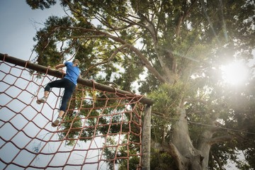 Woman climbing a net during obstacle course
