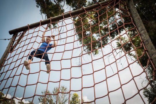 Woman climbing a net during obstacle course